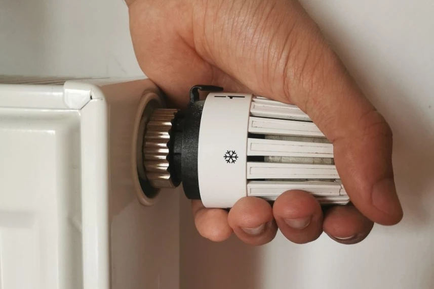 Dłoń na głowicy termostatycznej, która służy do regulowania temperatury w pomieszczeniu.