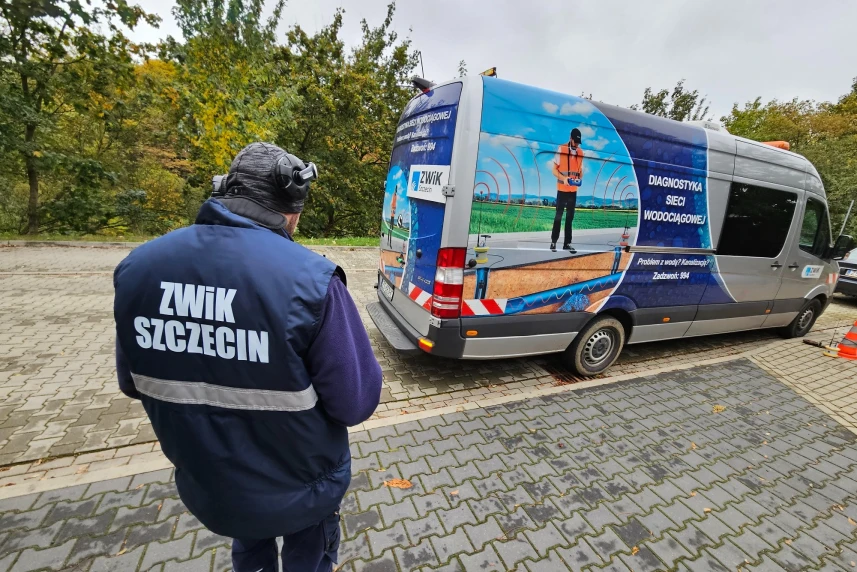 Pracownik ZWIK-u Szczecin. W głębi samochód służbowy