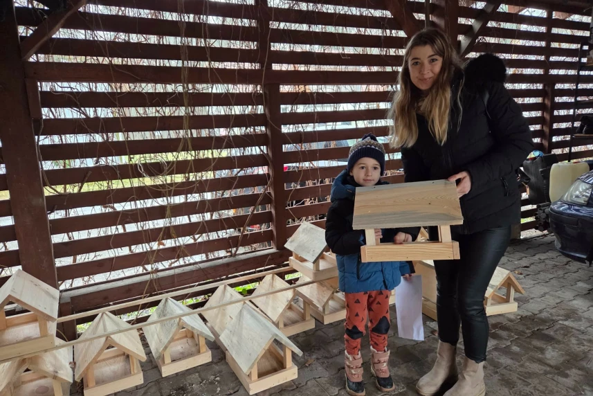 Młoda kobieta z dzieckiem odbiera karmnik dla ptaków.