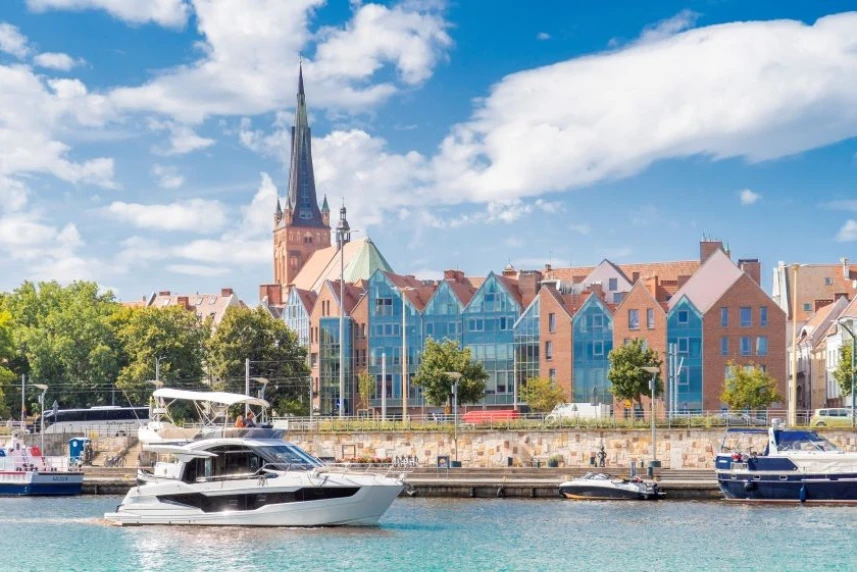 Jacht płynący Odrą, na tle panoramy Szczecina.