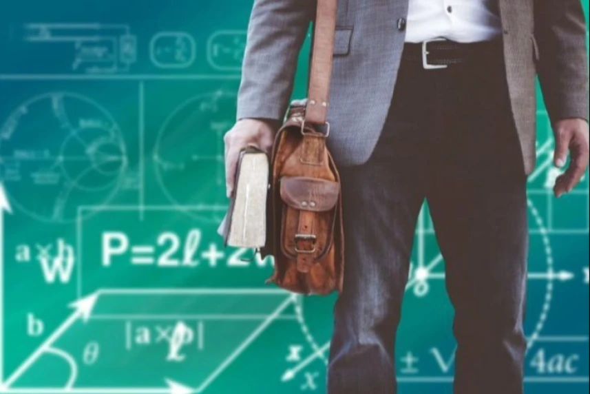 Student trzymający w ręku grubą książkę. Na ramieniu ma zawieszoną brązową torbę.