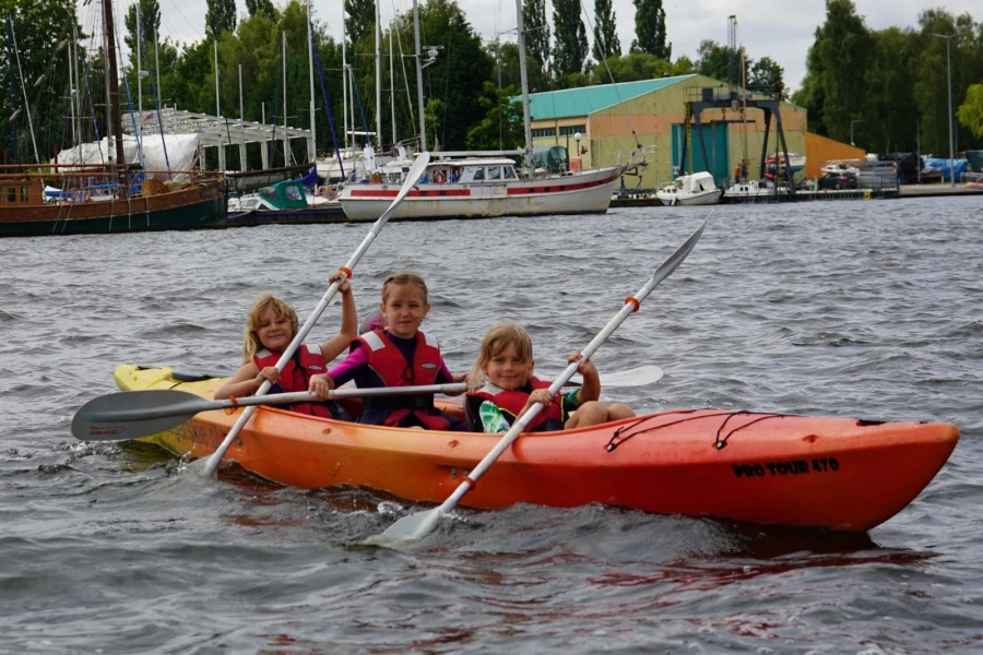 Trójka dzieci w zółto-pomarańczowym kajaku. Trójka dzieci w zółto-pomarańczowym kajaku.