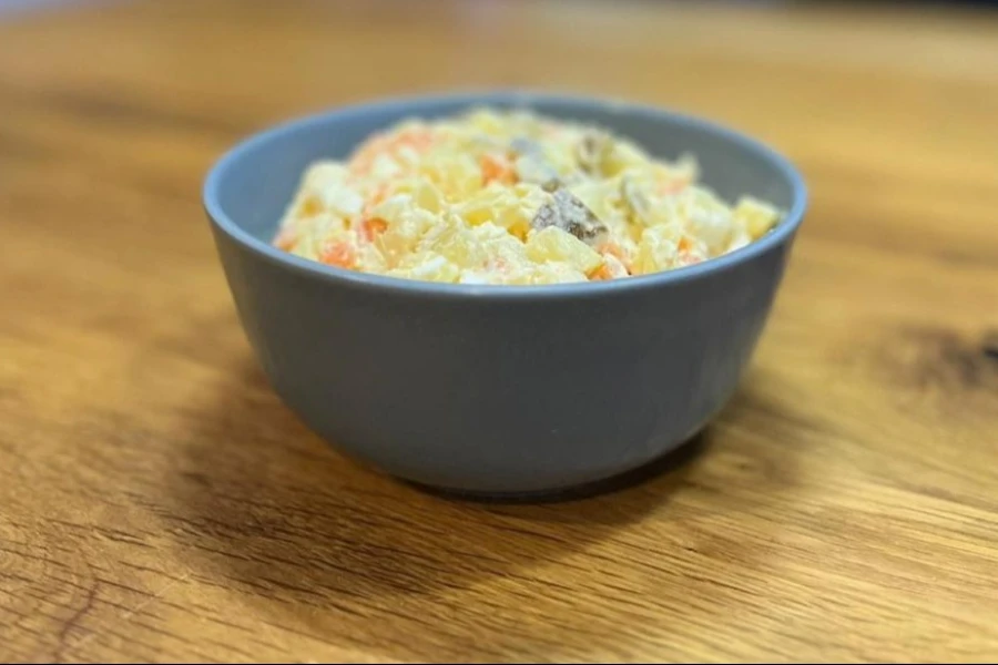 Salaterka z sałatką jarzynowo stojąca na blacie.