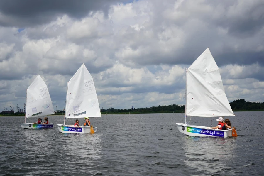 Trzy żaglówki na akwenie wodnym.