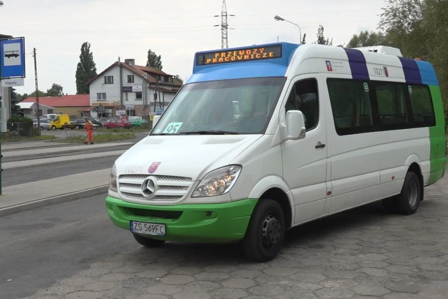 Biało-zielony mikrobus stojący na przystanku autobusowym.