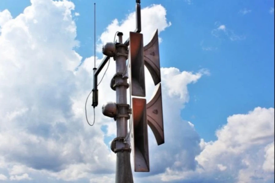 Syrena alarmowa na tle nieba pokrytego białymi chmurami