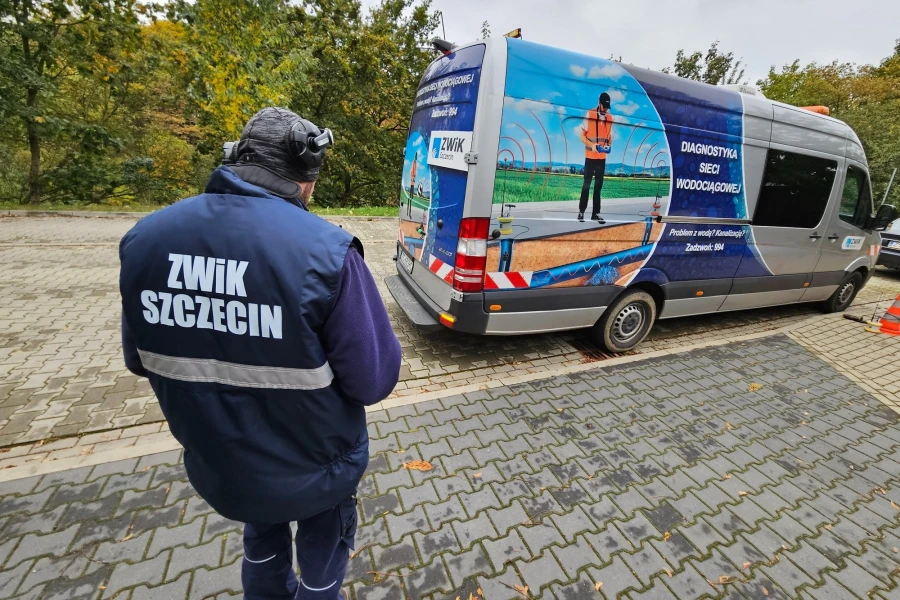 Pracownik ZWIK Szczecin stojący przy samochodzie służbowym.