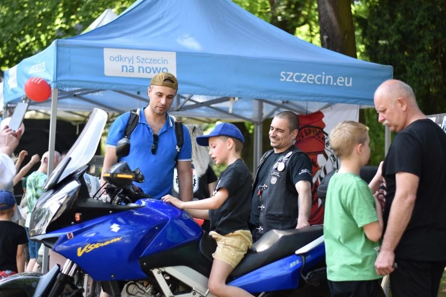 Chłopiec siedzący na motorze w otoczeniu innych osób.