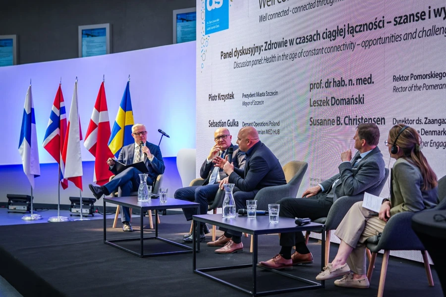 Pięć osób siedzących przy stolikach podczas debaty.