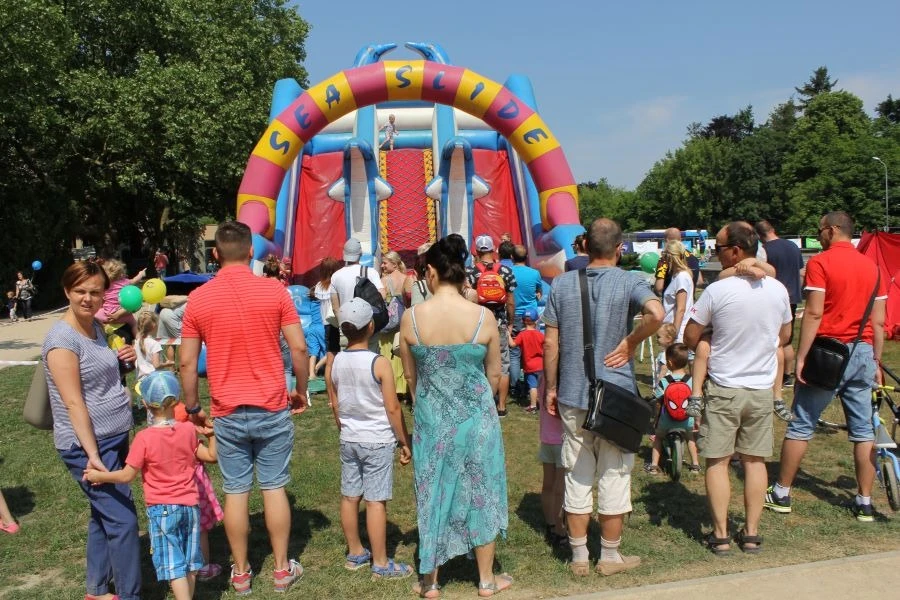 Grupa ludzi stojąca przed dmuchanymi atrakcjami dla dzieci