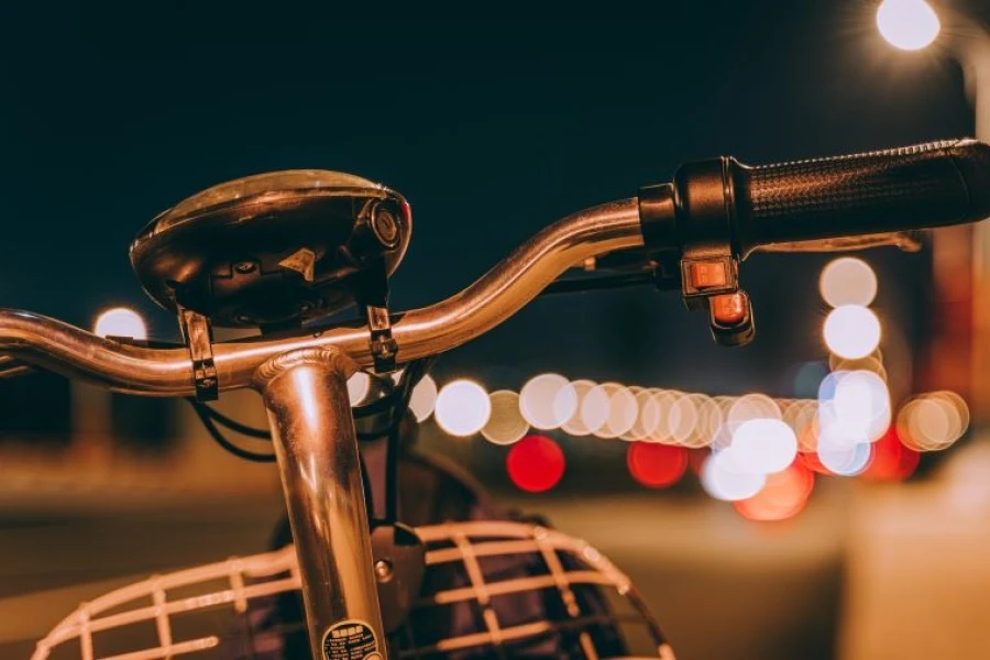 Kierownica rowerowa na tle oświetlonej wieczorem ulicy. Kierownica rowerowa na tle oświetlonej wieczorem ulicy.