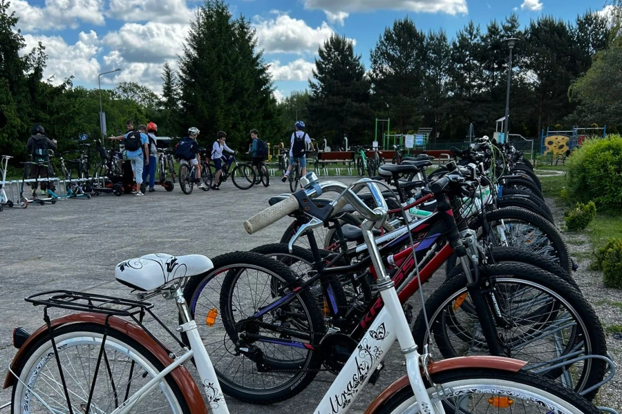 Szkolny parking rowerowy. W tle młodzi rowerzyści.