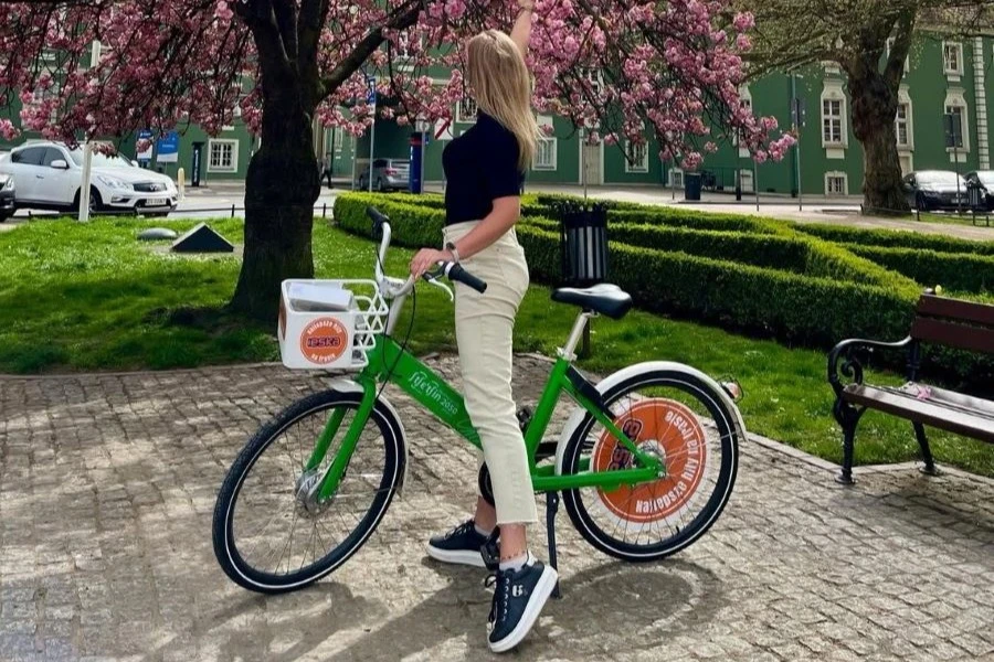 Kobieta w jasnych spodniach i ciemnej bluzce na zielonym rowerze. Kobieta w jasnych spodniach i ciemnej bluzce na zielonym rowerze.