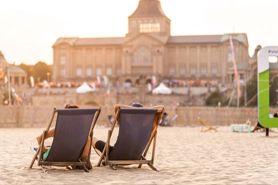 Dwa leżaki plażowe. W tle duży budynek.