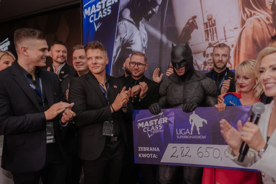 Grupa ludzi. W środku mężczyzna w stroju Batmana. Grupa ludzi. W środku mężczyzna w stroju Batmana.